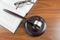 Judge gavel with sound board, open book and glasses on a wooden Royalty Free Stock Photo