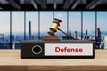 judge gavel standing on black office binder file folder on wooden desk in large modern office building defense label skyline