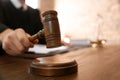 Judge with gavel at table in courtroom, closeup Royalty Free Stock Photo