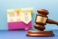 Judge gavel and upside-down toy house on table, real estate arrest concept