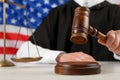 Judge with gavel at white wooden table against flag of United States, closeup Royalty Free Stock Photo