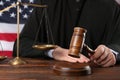 Judge with gavel at wooden table near flag of United States, closeup Royalty Free Stock Photo