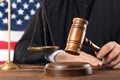 Judge with gavel at wooden table near flag of United States, closeup Royalty Free Stock Photo