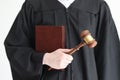 Judge in gown holds constitution and wooden gavel in studio