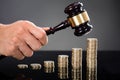 Judge Hands Hitting Gavel On Stacked Coins