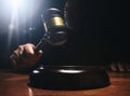 Judge hitting Gavel off a block in courtroom, dark background