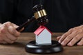 Judge Holding Gavel On House At Desk Royalty Free Stock Photo