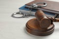 Judge`s gavel, handcuffs and books on wooden background. Criminal law concept