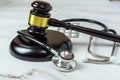 The Intersection of Law and Healthcare. A Close-Up Image of a JudgeÃ¢â¬â¢s Hand Holding a Stethoscope Next to a Gavel