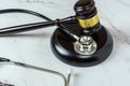 The Intersection of Law and Healthcare. A Close-Up Image of a JudgeÃ¢â¬â¢s Hand Holding a Stethoscope Next to a Gavel