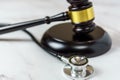 The Intersection of Law and Healthcare. A Close-Up Image of a JudgeÃ¢â¬â¢s Hand Holding a Stethoscope Next to a Gavel