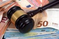 Judge`s gavel resting on euro banknotes close-up