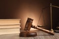 Judge`s gavel with sound block, scales of justice and books on wooden table against brown background Royalty Free Stock Photo