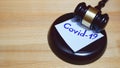 Judges gavel or law mallet and word covid-19 on sound block on wooden background.