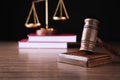 Judges gavel, scales and books on wooden table against black background Royalty Free Stock Photo