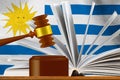 Judicial gavel on the background of an open book and the flag of Uruguay