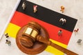 Judicial hammer, flag of Germany and plastic toy men on abstract background, concept of trial in german society