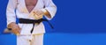 Judo fighter poses in white kimono with black belt. Japanese judo and jiu jitsu Royalty Free Stock Photo