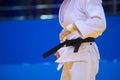 Judo fighter poses in white kimono with black belt. Japanese judo and jiu jitsu