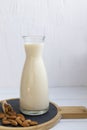 Jug with almond milk with scoop of almond on wooden board on white background Royalty Free Stock Photo