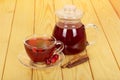 Jug with drink, cup tea rosehip berries on light wood. Royalty Free Stock Photo