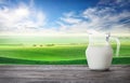 Jug of fresh milk against background of wavy pasture Royalty Free Stock Photo