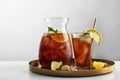 Jug and glass of delicious iced tea on table