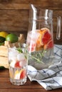 Jug and glass with refreshing grapefruit lemonade on wooden table