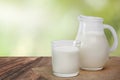 Jug of milk and glass milk on linen napkin on wooden table