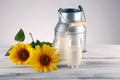 A jug of milk and glass of milk on a wooden table and flower