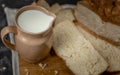 Jug of milk and a loaf of bread on a wooden board