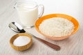 Jug of milk, bowl with raw rice, spoon, salt cellar on wooden table