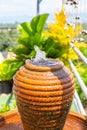 A jug with a water fountain on a background of tropical greenery. Decorative elements in the garden Royalty Free Stock Photo