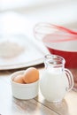 Jugful of milk, eggs in a bowl and flour