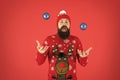 Juggle balls. Fun festive activities. Hipster cheerful bearded man wear winter sweater and hat hold balls red background