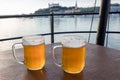 Jugs of beer placed on a wooden table on background river Danube and Bratislava castle, Slovakia Royalty Free Stock Photo