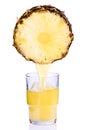 Juice being poured into a glass of pineapple