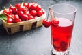 Juice or compote with cherries. fresh ripe red cherry in a basket on a gray concrete background, summer berry, space for text Royalty Free Stock Photo