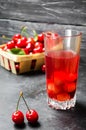 Juice or compote with cherries. fresh ripe red cherry in a basket on a gray concrete background, summer berry, space for text Royalty Free Stock Photo