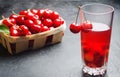 Juice or compote with cherries. fresh ripe red cherry in a basket on a gray concrete background, summer berry, summer drink Royalty Free Stock Photo