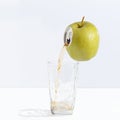 Juice flowing from a ripe apple into a glass. Creative concept of fresh juice