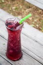 Juice mix berry fruit drink red purple color in tall glass with straw green color on wooden Royalty Free Stock Photo