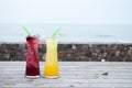 Juice mix berry, mango and passion fruit drink in tall glass with straw green color on wooden terrace Royalty Free Stock Photo