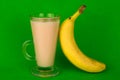 Juice, nectar from a banana in a glass on a bright green background.