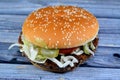 A juicy beef patty with cheese covered with sauce, crispy lettuce, fresh tomatoes, onions and pickles in a large sesame seed bun, Royalty Free Stock Photo