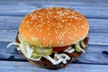 A juicy beef patty with cheese covered with sauce, crispy lettuce, fresh tomatoes, onions and pickles in a large sesame seed bun, Royalty Free Stock Photo