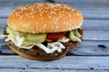 A juicy beef patty with cheese covered with sauce, crispy lettuce, fresh tomatoes, onions and pickles in a large sesame seed bun, Royalty Free Stock Photo