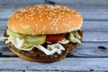 A juicy beef patty with cheese covered with sauce, crispy lettuce, fresh tomatoes, onions and pickles in a large sesame seed bun, Royalty Free Stock Photo