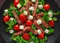 Juicy Beef Sirloin Steak Salad with roasted tomatoes, feta cheese and green vegetables in a black plate. healthy food Royalty Free Stock Photo