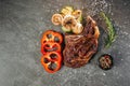 Juicy beef steak on a dark metal cutting board, next to a sprig of aromatic rosemary, a black pot of peppercorn mix, three slices Royalty Free Stock Photo